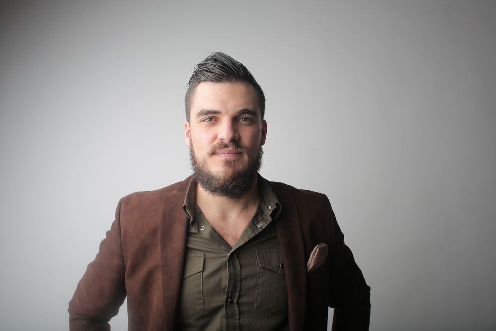 man with brushed back hairstyle and trimmed beard