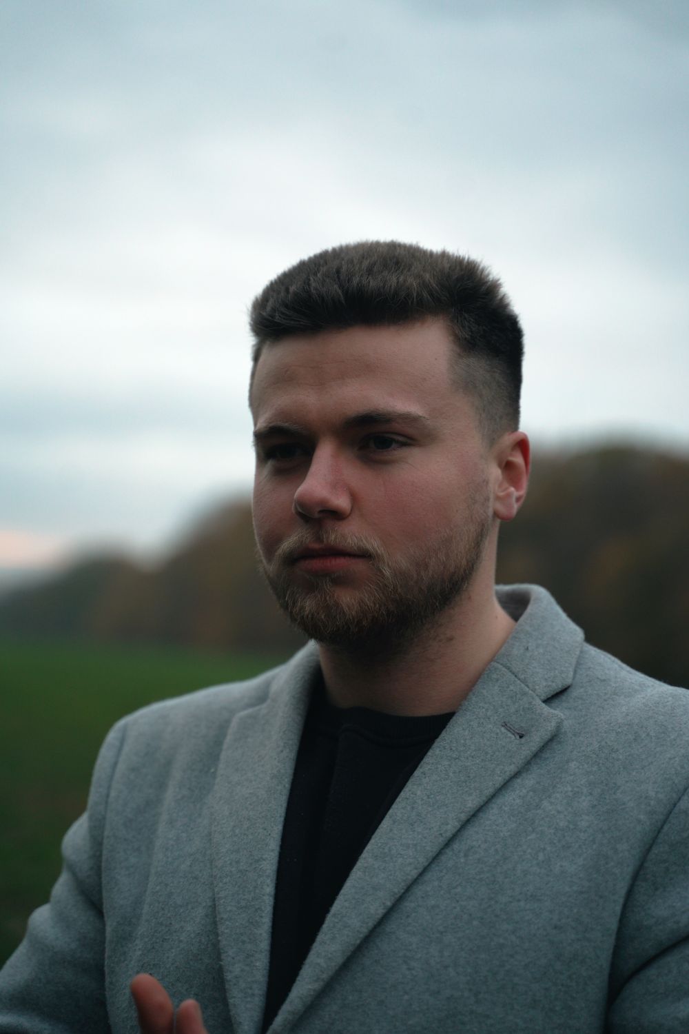 bearded man with a short tapered haircut wearing a gray blazer