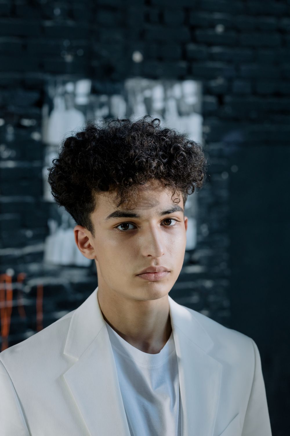 man with a medium curly hairstyle and clean blazer look