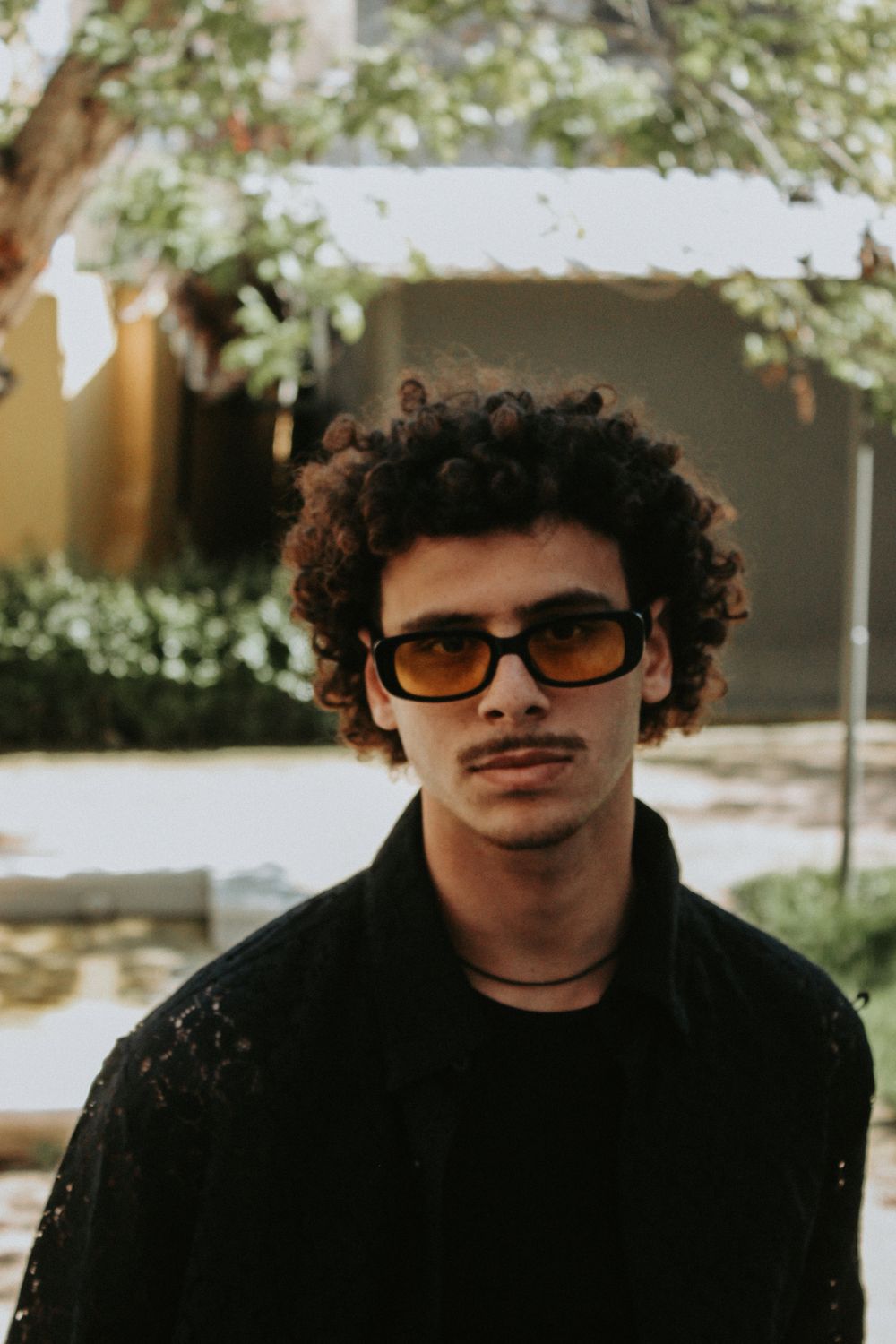 man with a compact curly haircut wearing dark glasses