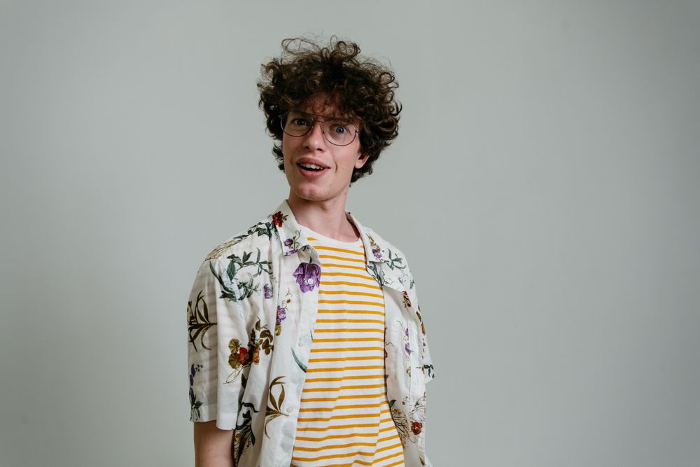 man wearing glasses with rounded medium curly hair