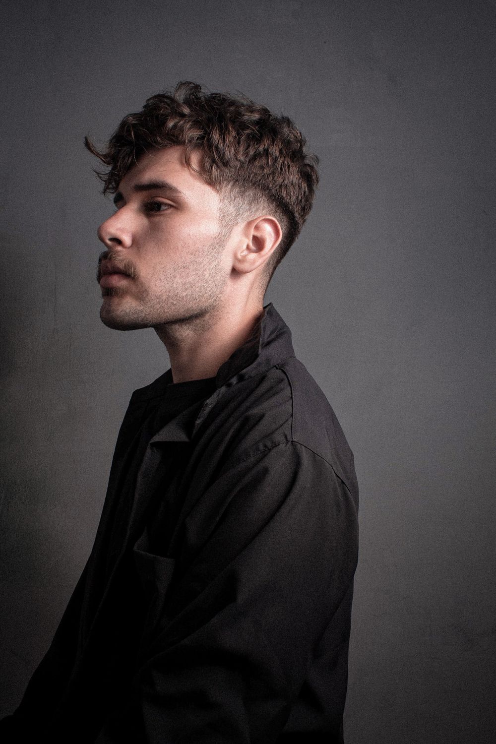 side profile of man with short curly fringe and tapered sides
