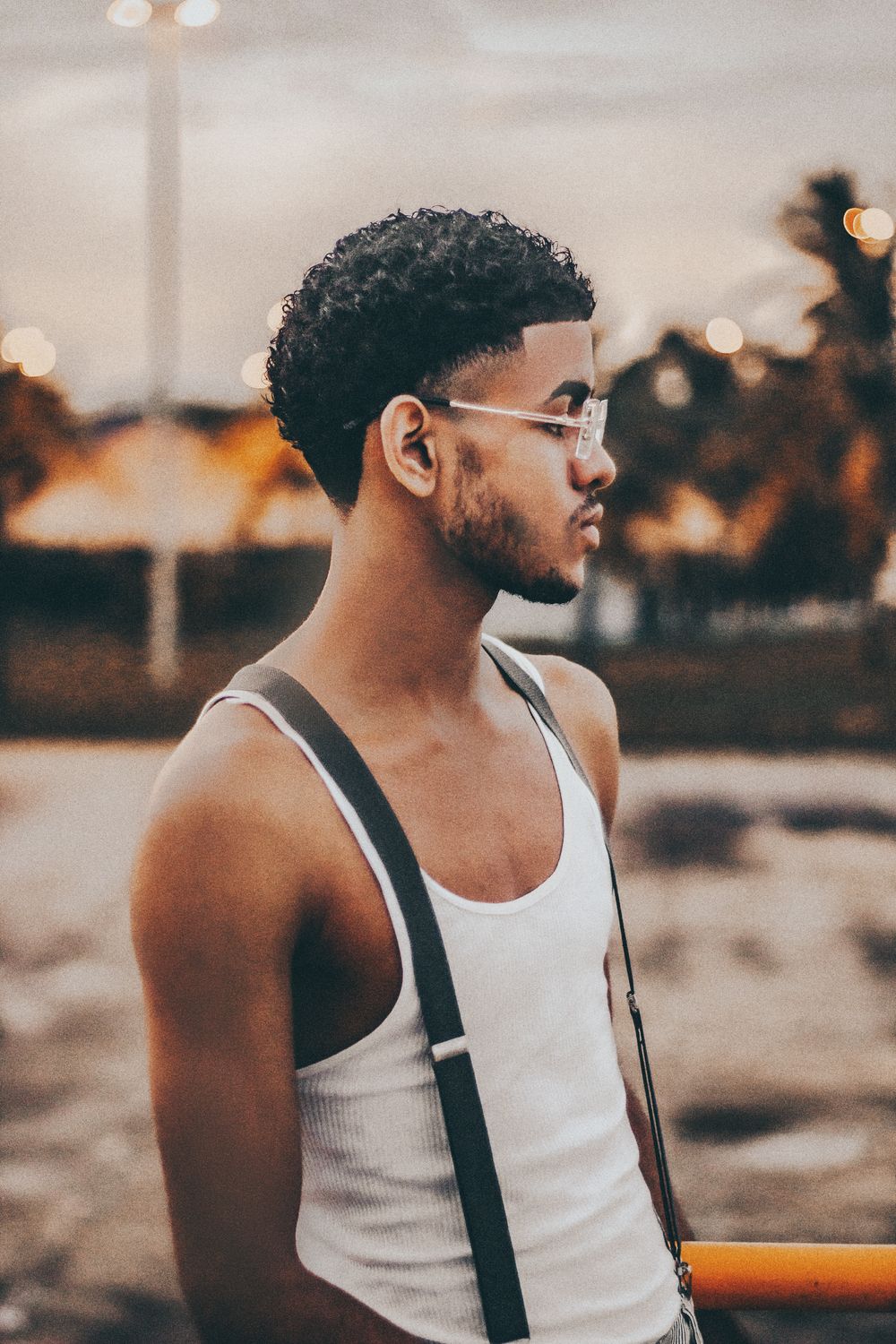 side profile of man wearing glasses with curly hair and faded sides