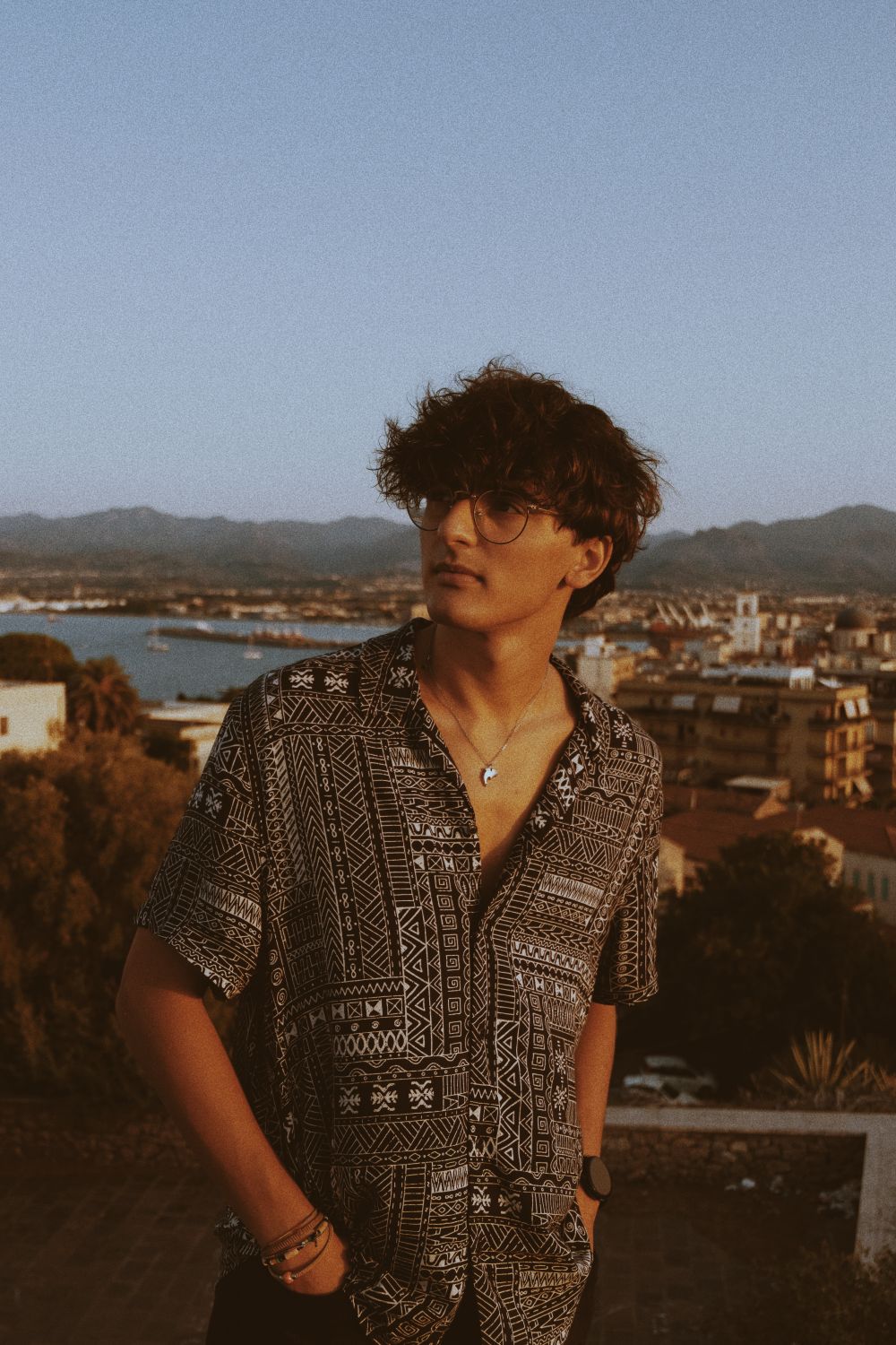 man with curly hair and glasses wearing a patterned shirt