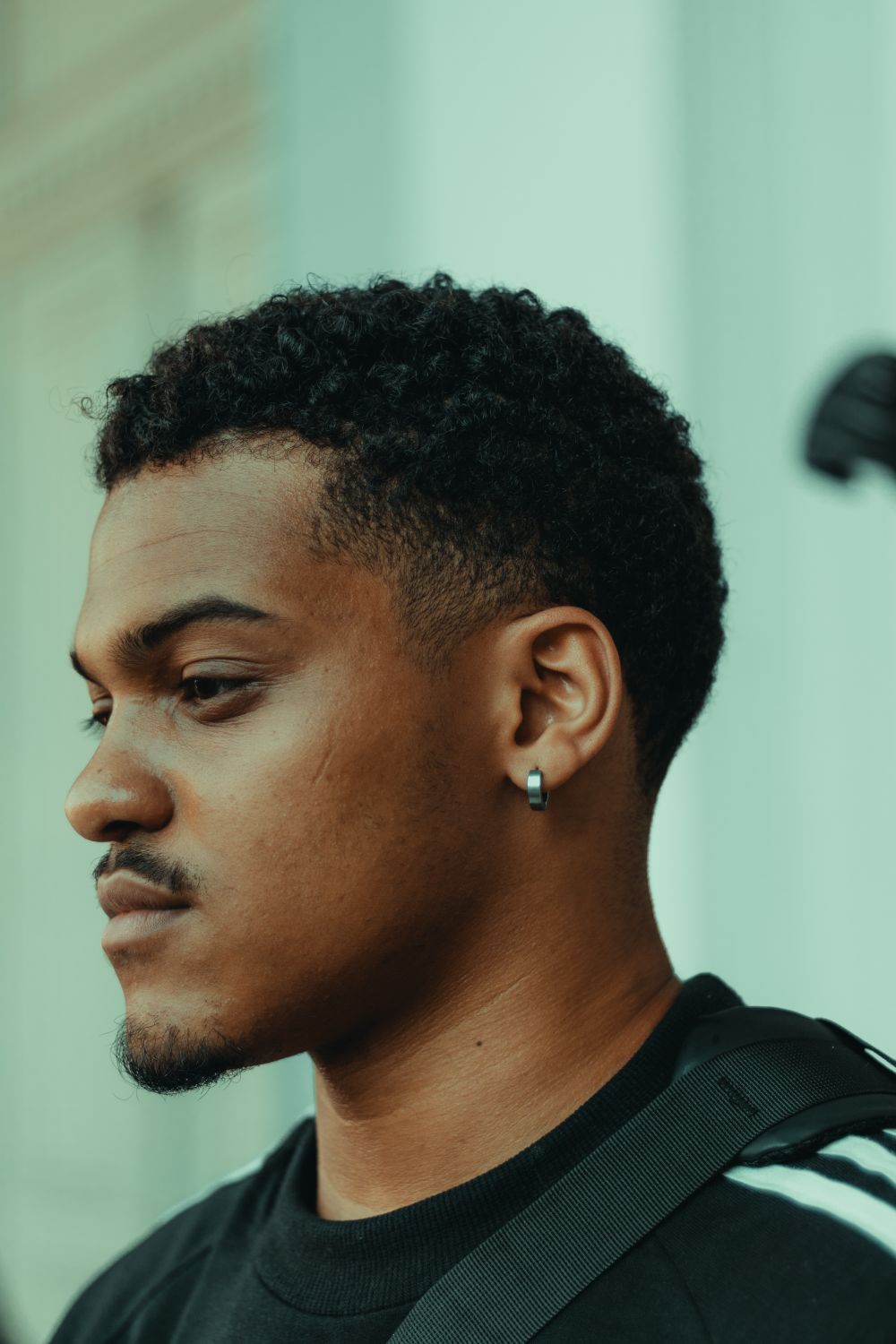 side profile of man with short curls and a low tapered fade