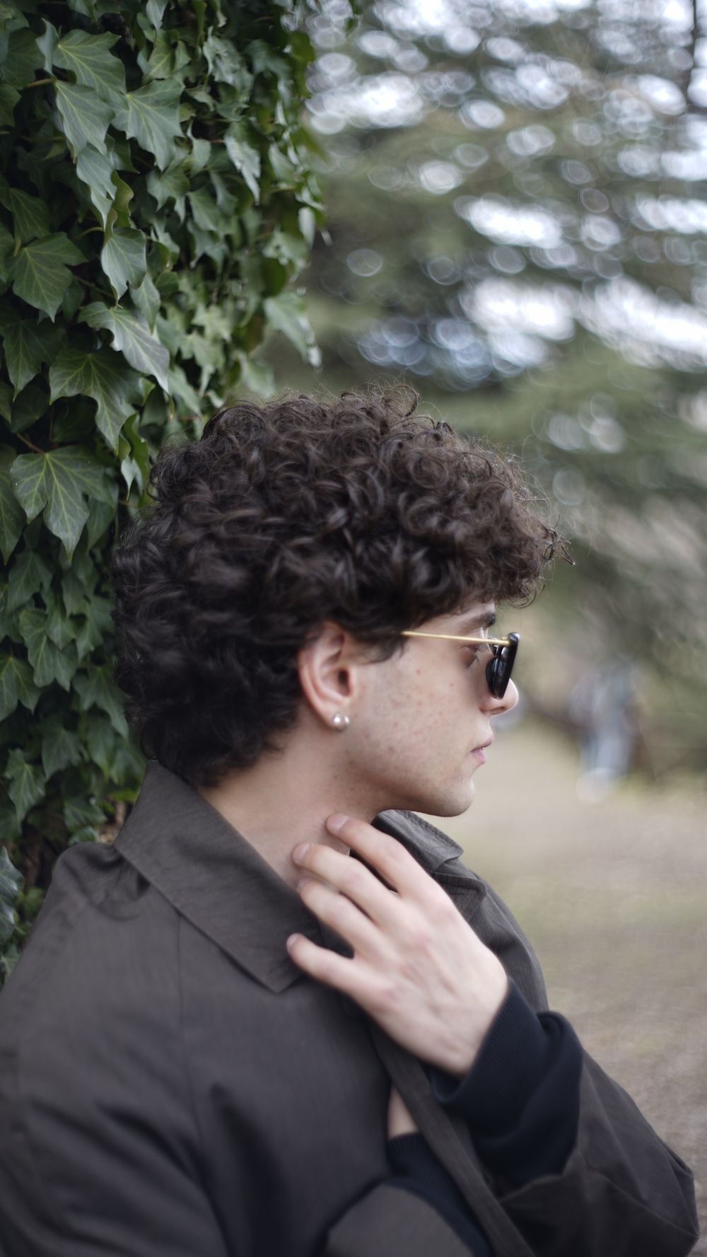 side profile of man with medium curly hair wearing sunglasses