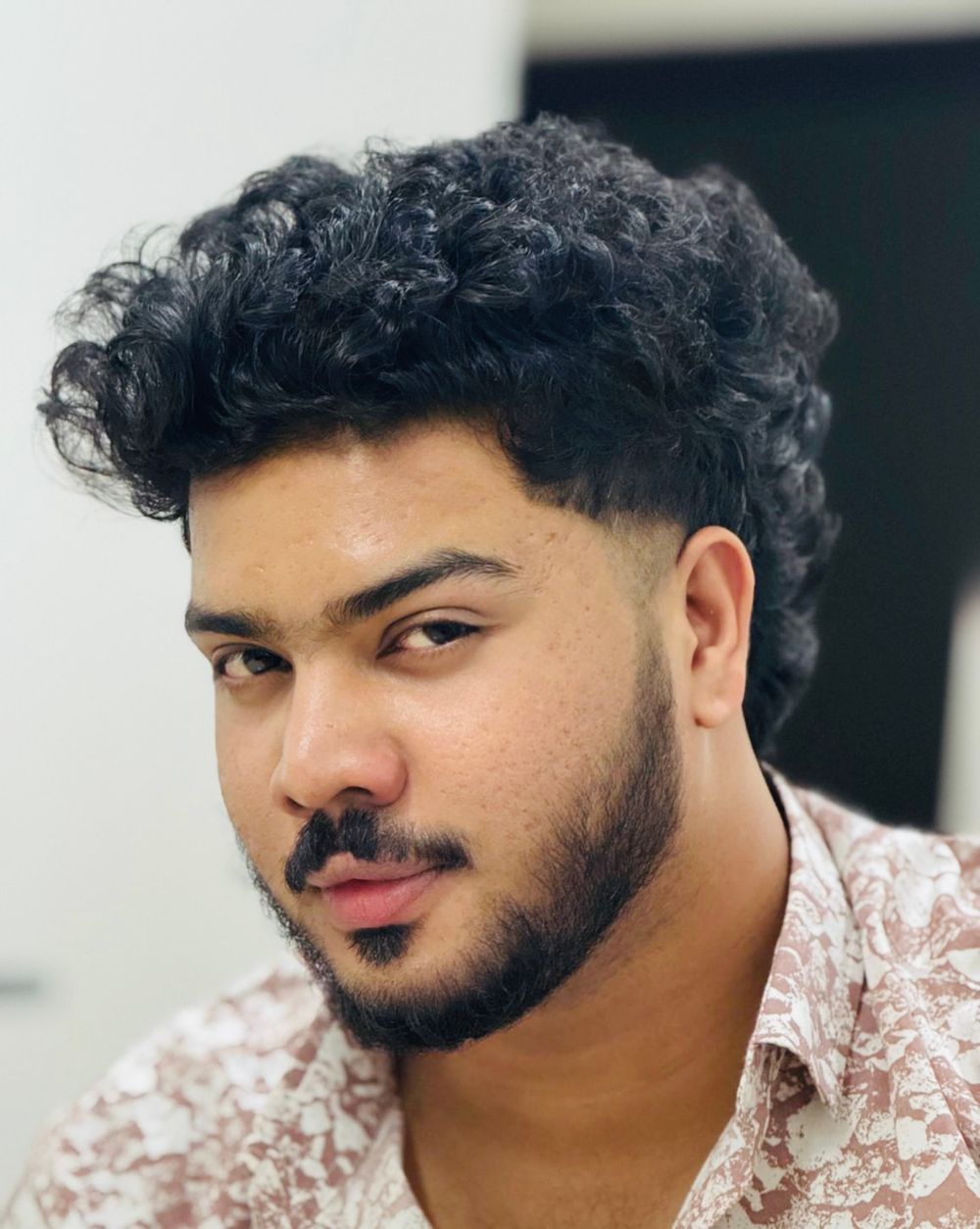 bearded man with short curly top and tapered fade