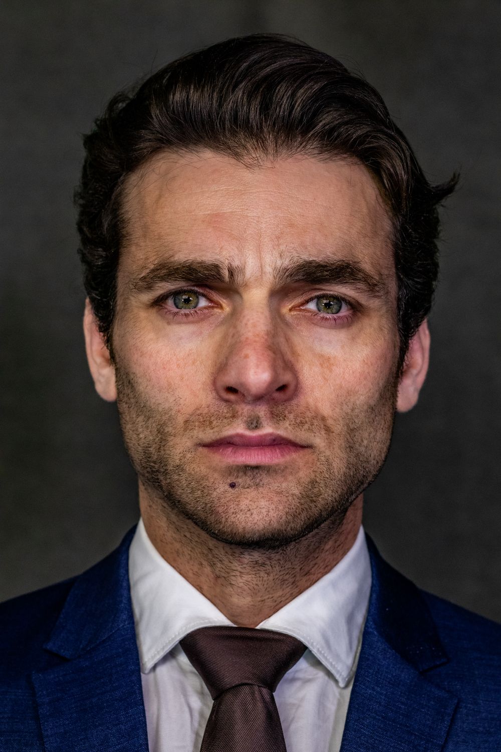 man in blue suit with medium brushed back hair