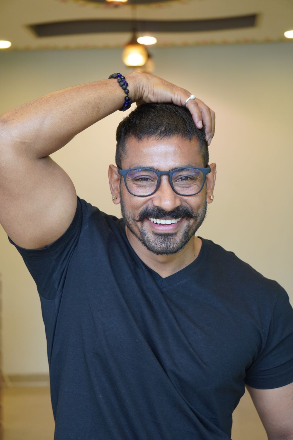 man wearing glasses with a short tapered hairstyle and mustache