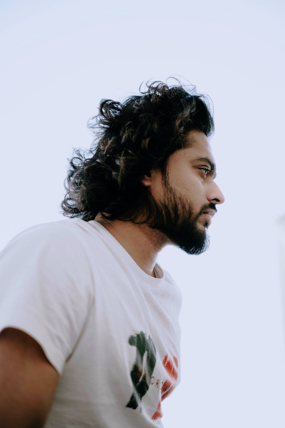 side profile of man with long wavy hair and beard