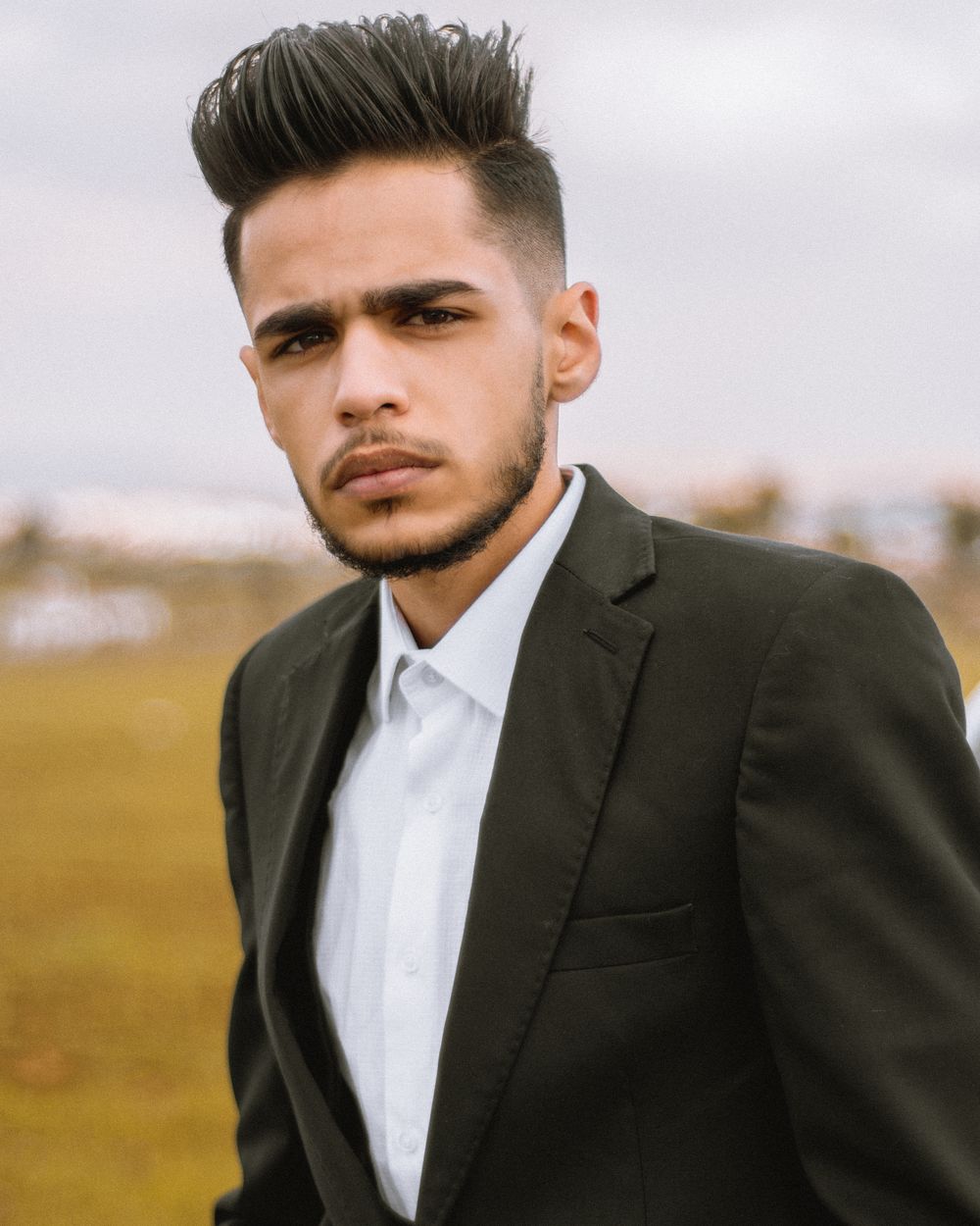 man in a dark suit with a polished short quiff hairstyle