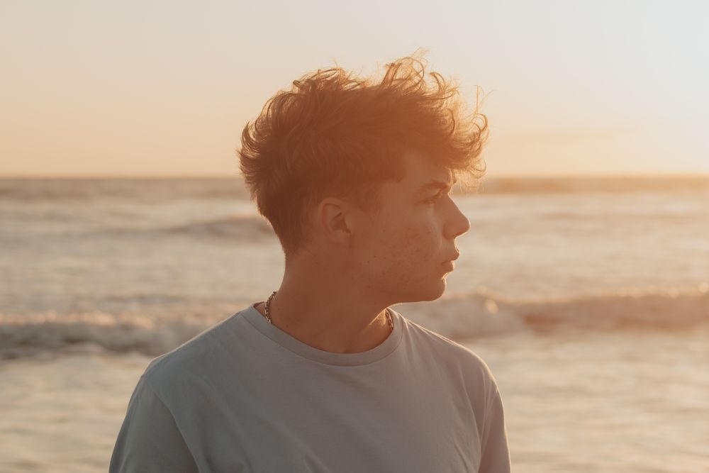 side profile of man with short wavy hair in warm sunlight