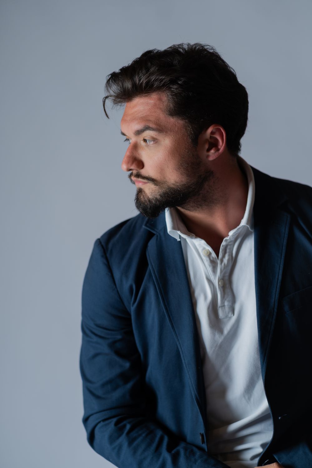 bearded man with medium wavy side swept hair and blazer